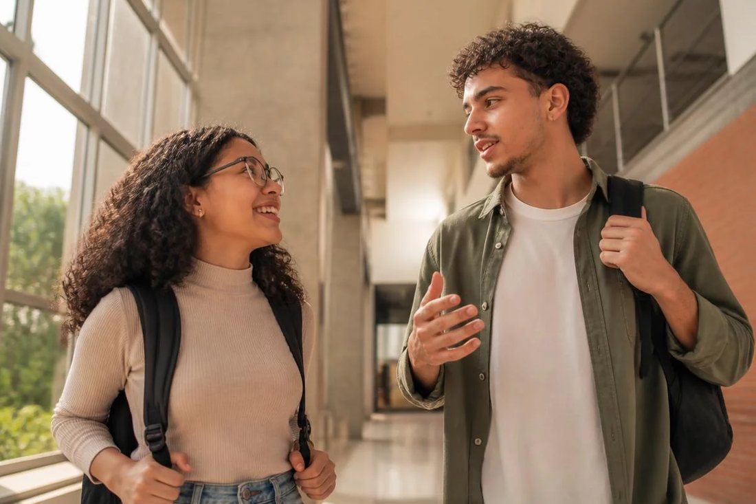 Dois estudantes de mochila continuam a discussão no corredor depois da sessão
